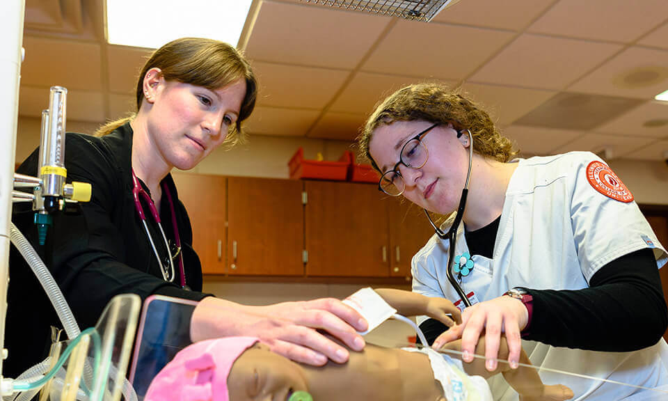 A student getting trained with examining a baby.